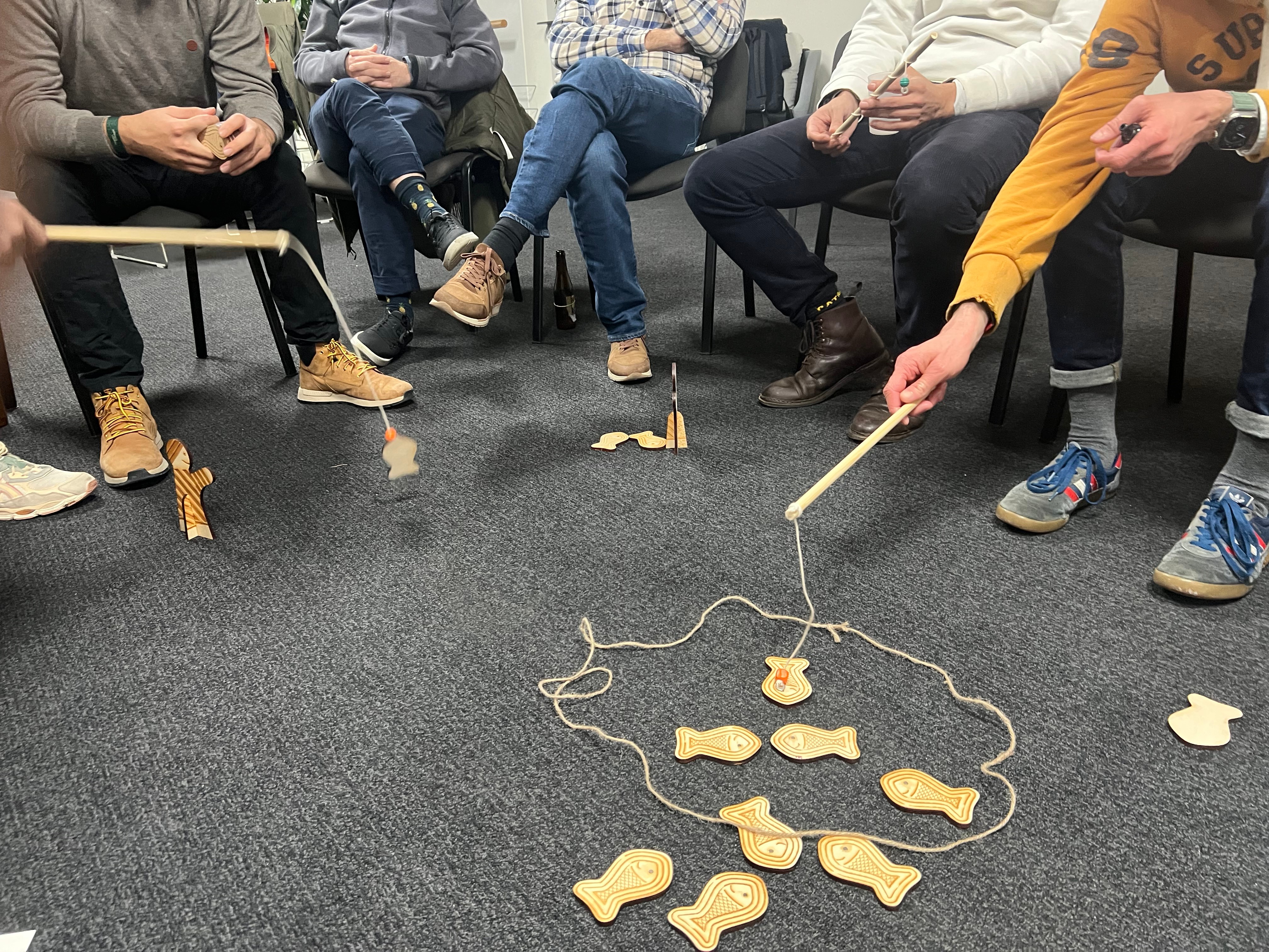 The Commons Game - participants fishing wooden fish from a shared pool